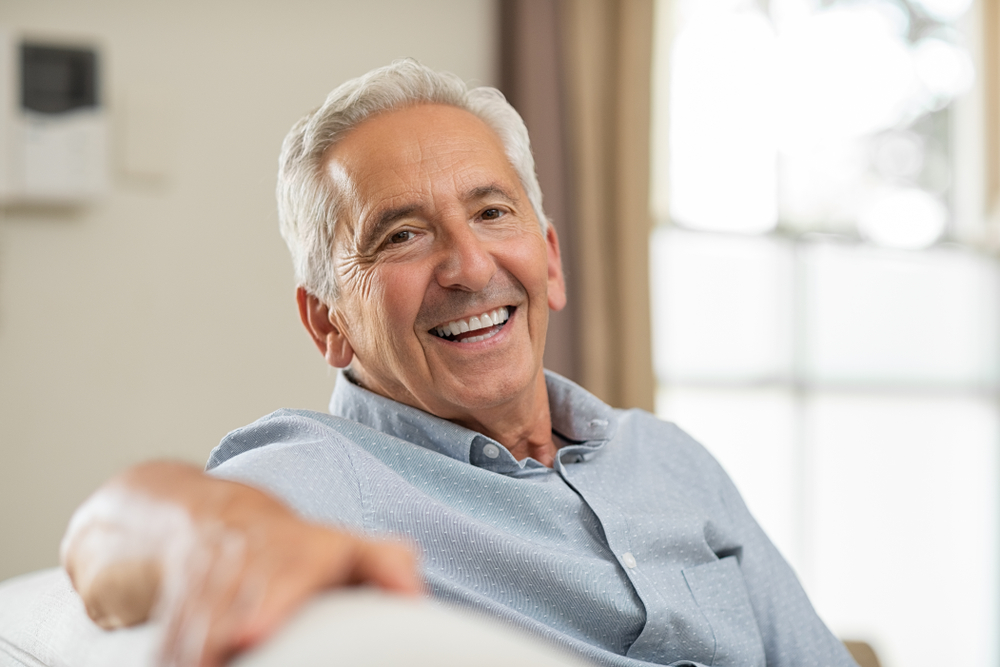 Smiling older man relaxed at home after Extraction Site Preservation treatment at Craft Dental.