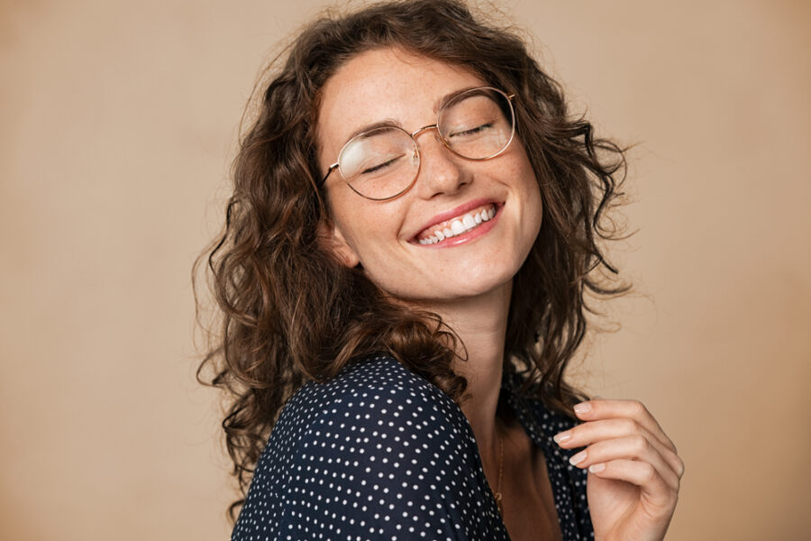 Happy woman with glasses smiling confidently after Arestin® periodontal treatment at Craft Dental