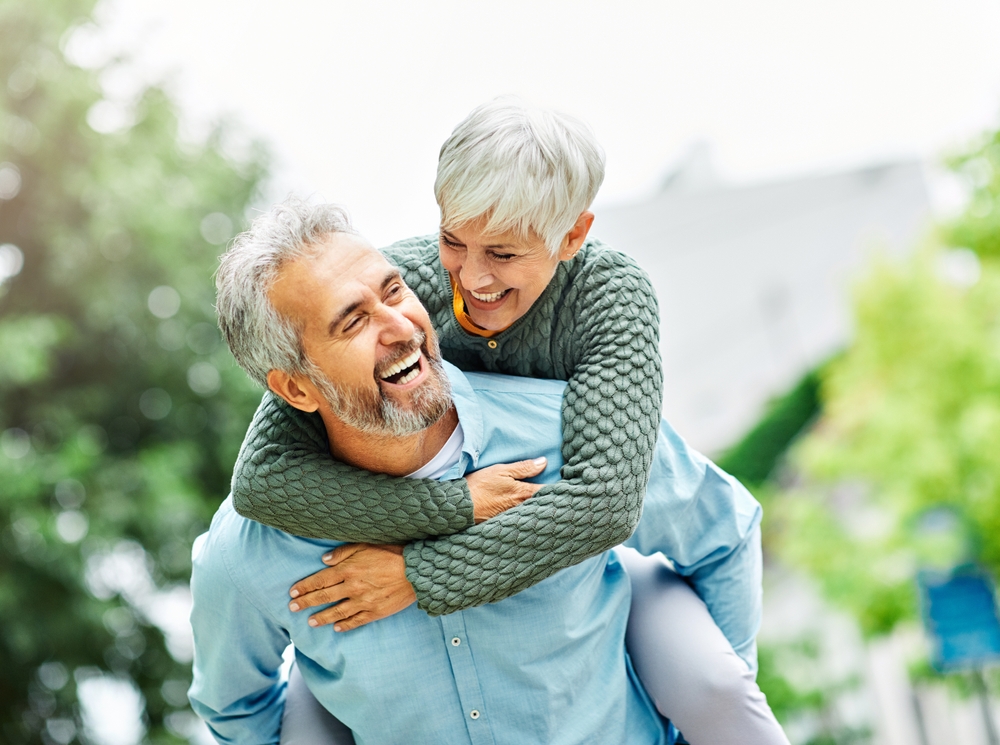 Joyful senior couple outdoors smiling brightly after receiving Cosmetic Dentistry treatment at Craft Dental.