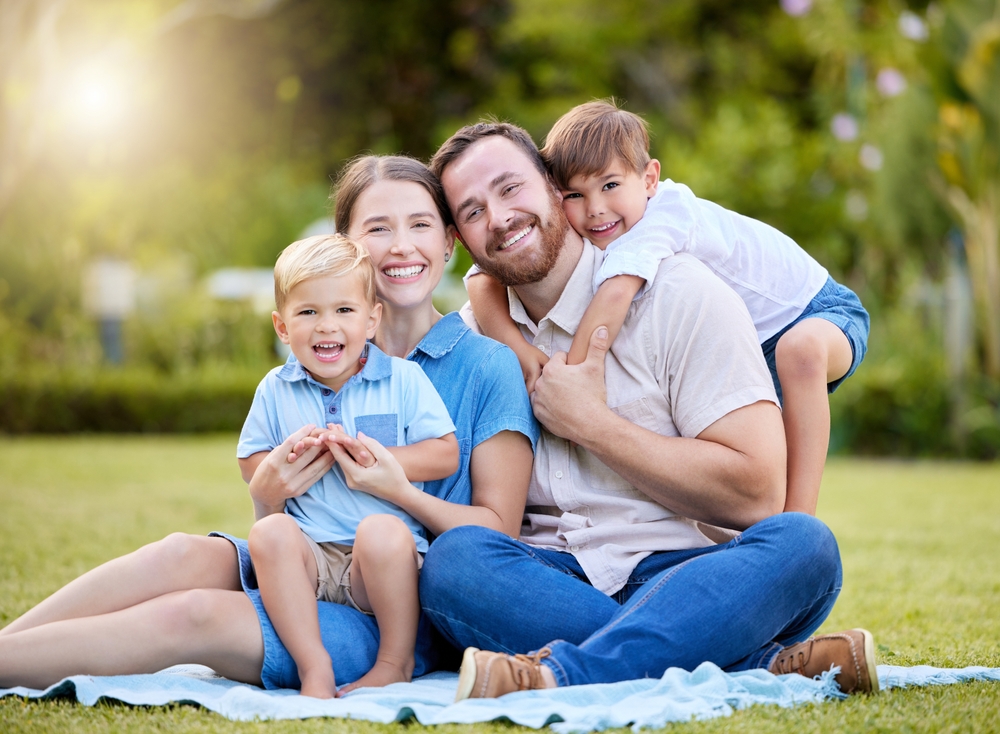 Smiling family sitting outdoors together after receiving prompt Emergency Dentistry care at Craft Dental