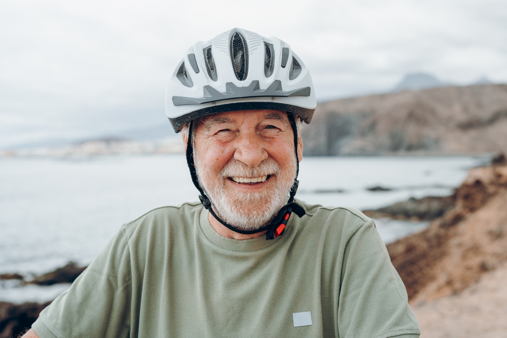 Smiling senior man outdoors wearing helmet after successful Oral Surgery treatment at Craft Dental
